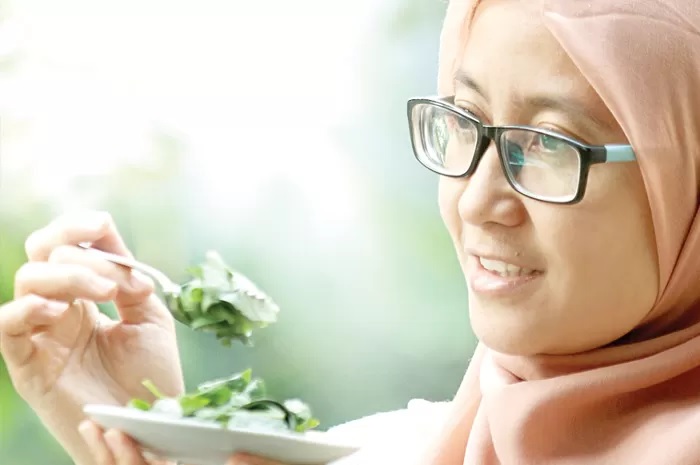 BERKHASIAT: Farah mengonsumsi daun ginseng jawa secara langsung. Salah satu khasiatnya untuk relaksasi otot rahim. (Frizal/Jawa Pos)