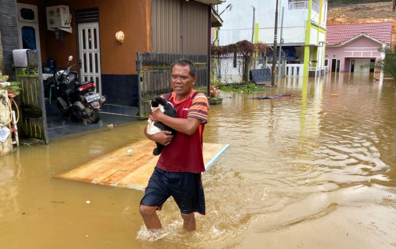 Heri menggendong kucing kesayangannya untuk dievakuasi pada Jum