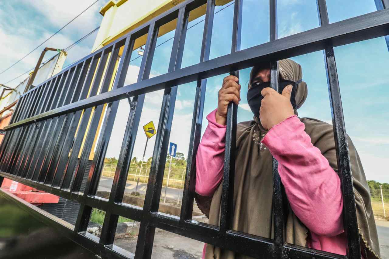 SETIA MENUNGGU: Warga Teras Baru, Siti, setiap sore dalam 4 hari terakhir menunggu suaminya di depan pagar kantor Diklat Jalan Agatis, yang sudah dinyatakan negatif Covid 19 dari proses screening, Senin (6/4).