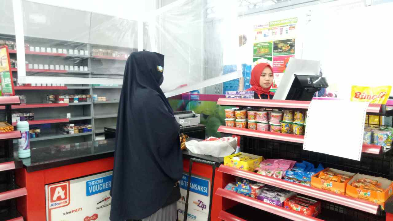 TELAH BEROPERASI: Petugas kasir mini market Alfamidi melayani customer yang akan membayar.