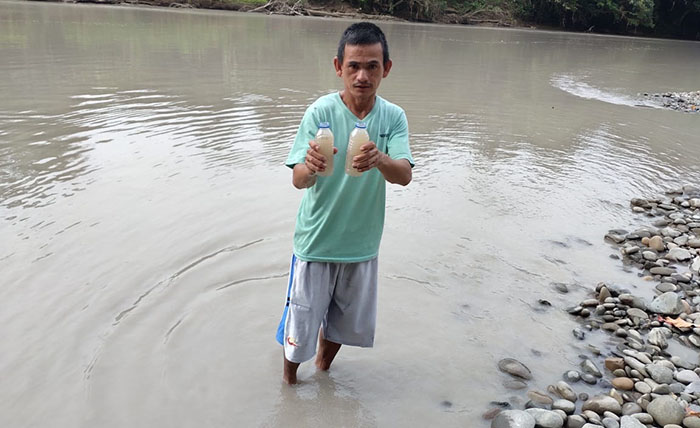 TERCEMAR: Warga memperlihatkan air sungai yang tercemar akibat limbah perusahaan.