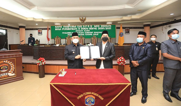 DISAHKAN: Wali Kota Tarakan Khairul dan Ketua DPRD Tarakan Al Rhazali memperlihatkan penandatangan berita acara pengesahan Raperda menjadi Perda Zakat, Selasa lalu (23/2).