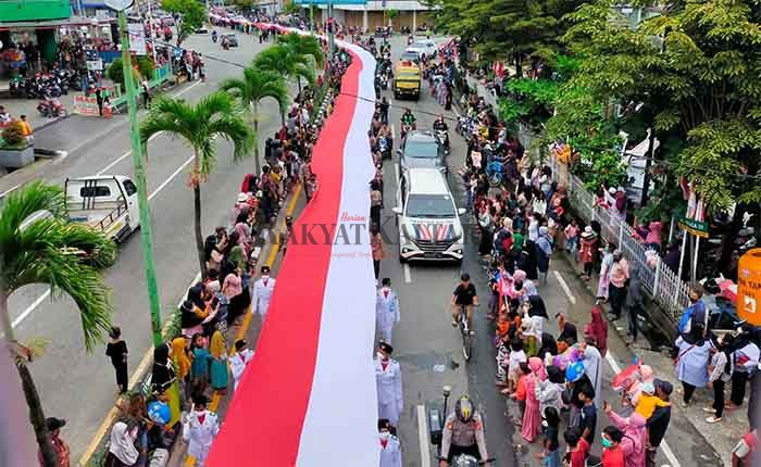KIRAB MERAH PUTIH: Warga membawa Bendera Merah Putih sepanjang 500 meter dan lebar 2,20 meter dari Jalan Mulawarman menuju Jalan Yos Sudarso. Minggu (19/12).