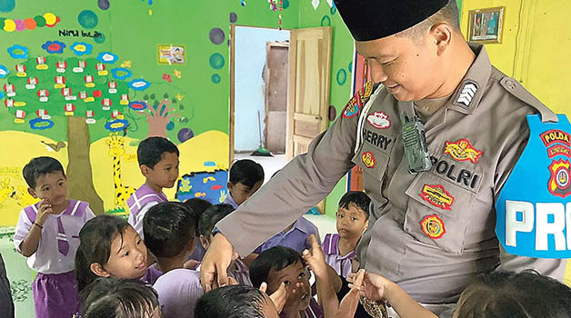 PEDULI PENDIDIKAN: Bripka Heri menyalami para murid TK Bumi Damai Indonesia, Dukuh Krambil, Gunungkidul.