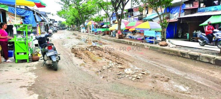 Jalan berlubang ditutup tanah, namun karena hujan makin membuat becek dan licin.