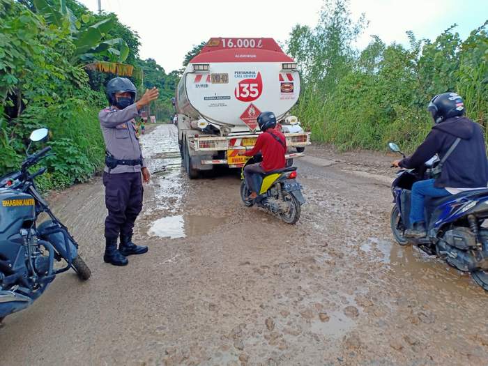 INGATKAN WARGA: Anggota Bhabinkamtibmas Kelurahan Loa Buah, Aiptu Roni Eko mengatur lalu lintas lantaran kondisi jalanan yang rusak.