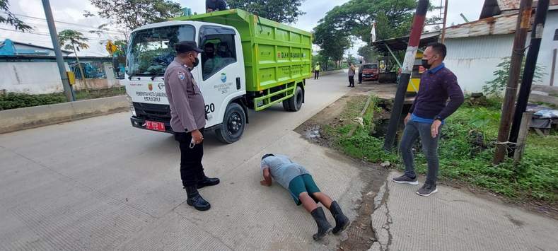 TAK PANDANG BULU. Seorang petugas lapangan bagian kebersihan DLH Samarinda diminta melakukan push up karena kedapatan tak memakai masker saat menjalankan tugasnya, ketika melintas di depan Mapolsekta Sungai Kunjang. (Hagusman/Sapos)