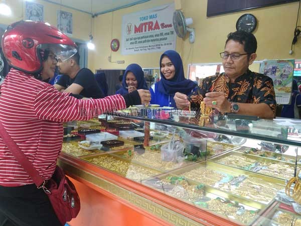 PAMERKAN : Hj. Sani sedang menimbang emas 999 didepan pelanggan.