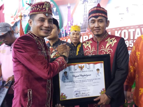 SERAHKAN: Bupati Kotim Supian Hadi saat menyerahkan penghargaan salah satu instansi terbaik di Kotim, Dinas Pekerjaan Umum dan Penataan Ruang (PUPR) Kotim, diterima oleh Mentana, beberapa waktu lalu.(DESIWULANDARI/RADARSAMPI)