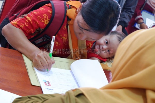 DEMI BUAH HATI: Marina salah seorang peserta tes CPNS dari Kecamatan Bukit Santuai, membawa anaknya, saat mengambil kartu peserta tes di Badan Kepegawaian Daerah Kotawaringin Timur, beberapa waktu lalu.(DOK. USAY NOR RAHMAD/RADAR SAMPIT)