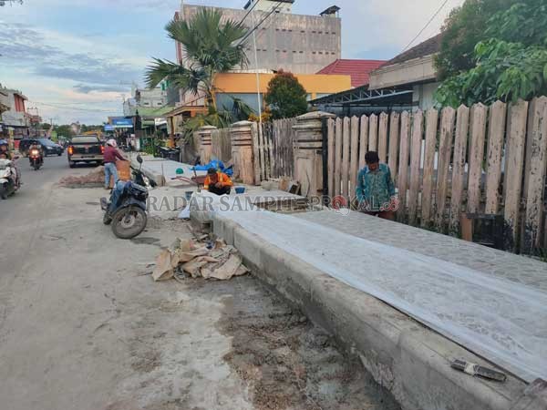 SALURAN: Terlihat para pekerja masih melakukan proses pemasangan keramik, yang nantinya digunakan untuk pejalan kaki, buka pedagang, Minggu (23/2).(DIANTARESA/RADARSAMPIT)