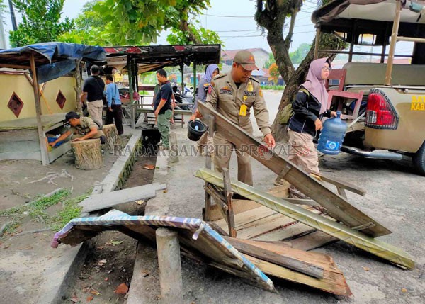 DIBONGKAR : Anggota Satpol PP dan Damkar membongkar lapak PKL di Bundaran Gentong samping SMKN 1 Pangkalan Bun Kelurahan Madurejo, Kamis (12/3) SATPOL PP /RADAR PANGKALAN BUN
