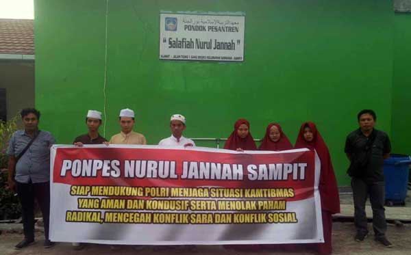 KAMTIBMAS: Ketua Ponpes Nurul Jannah Ustad Abdul Ghofur (tengah) beserta santriwan dan santriwatinya saat melakukan kegiatan pemasangan spanduk imbauan tolak paham radikal, di Ponpes Nurul Jannah, Senin (30/3) kemarin.(AHRY/RADAR SAMPIT)