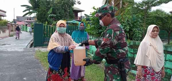 BERBAGI: Tim Satgas Covid-19 dari Anggota TNI sedang membagikan cairan disinfektan kepada warga Kelurahan Pahandut, Rabu (8/4).(DPKP/RADAR PALANGKA)