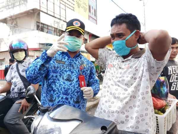 BANTUAN: Sekda Kotim Halikinnor sedang meminta pengguna motor untuk mengenakan masker, dan Sekretaris Korpri Kotim Emaliatun turut membagikan masker di persimpangan Jalan Pelita, Jumat (17/4).(DESIWULANDARI/RADARSAMPIT)