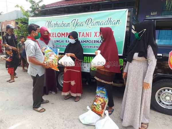 BANTUAN SOSIAL : Ketua LPMK Kotawaringin Hilir Musyawir saat menyerahkan paket sembako dari kelompok petani sawit kepada warga.(GUSTI HAMDAN/RADAR PANGKALAN BUN)