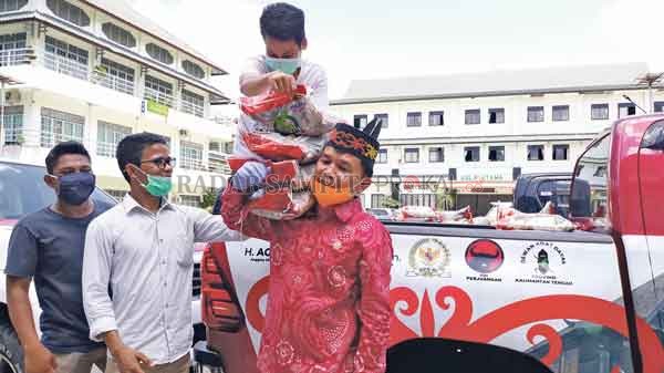 TURUN LANGSUNG: Agustiar Sabran ikut mengangkat langsung bantuan bahan pokok untuk mahasiswa UMP Palangka Raya.(DODI/RADAR SAMPIT)