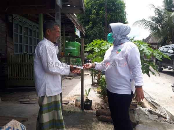 BAGIKAN MASKER : Bupati Kobar Hj Nurhidayah saat menyerahkan masker kepada salah seorang warga Kecamatan Kotawaringin Lama beberapa hari lalu.(GUSTI HAMDAN/RADAR PANGKALAN BUN)