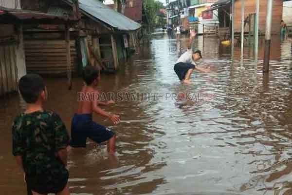 BANJIR: Terlihat anak - anak berlarian ditengah banjir yang merendam kawasan permukiman di wilayah Barito Utara, tanpa menghiraukan kondisi saat ini ditengah pandemi virus korona.(IST/RADARSAMPIT)