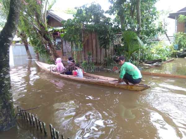 SAMPINGAN : Warga yang memanfaatkan jasa perahu getek, di tengah lingkungan yang dilanda banjir akibat meluapnya air Sungai Barito.( Alwandi/Radar Sampit)