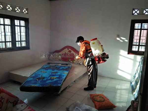 DISINFEKSI: Petugas sedang melakulan pembersihan dan disinfeksi kawasan mess desa setelah digunakan untuk karantina.(RIA MEKAR/RADAR SAMPIT)