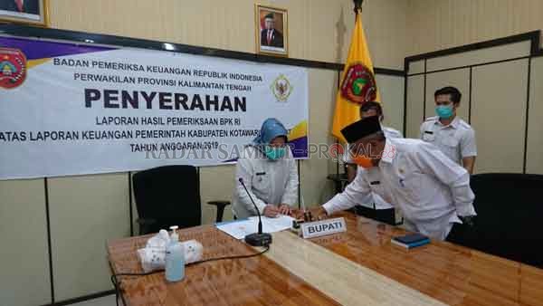 WAJAR TANPA PENGECUALIAN : Bupati Kobar Hj Nurhidayah menandatangani Berita Acara Penyerahan LHP BPK RI atas LKPD Tahun 2019 Kabupaten Kobar di ruang rapat Setda pada Rabu (20/5) siang.(DISKOMINFO/RADAR PANGKALAN BUN )