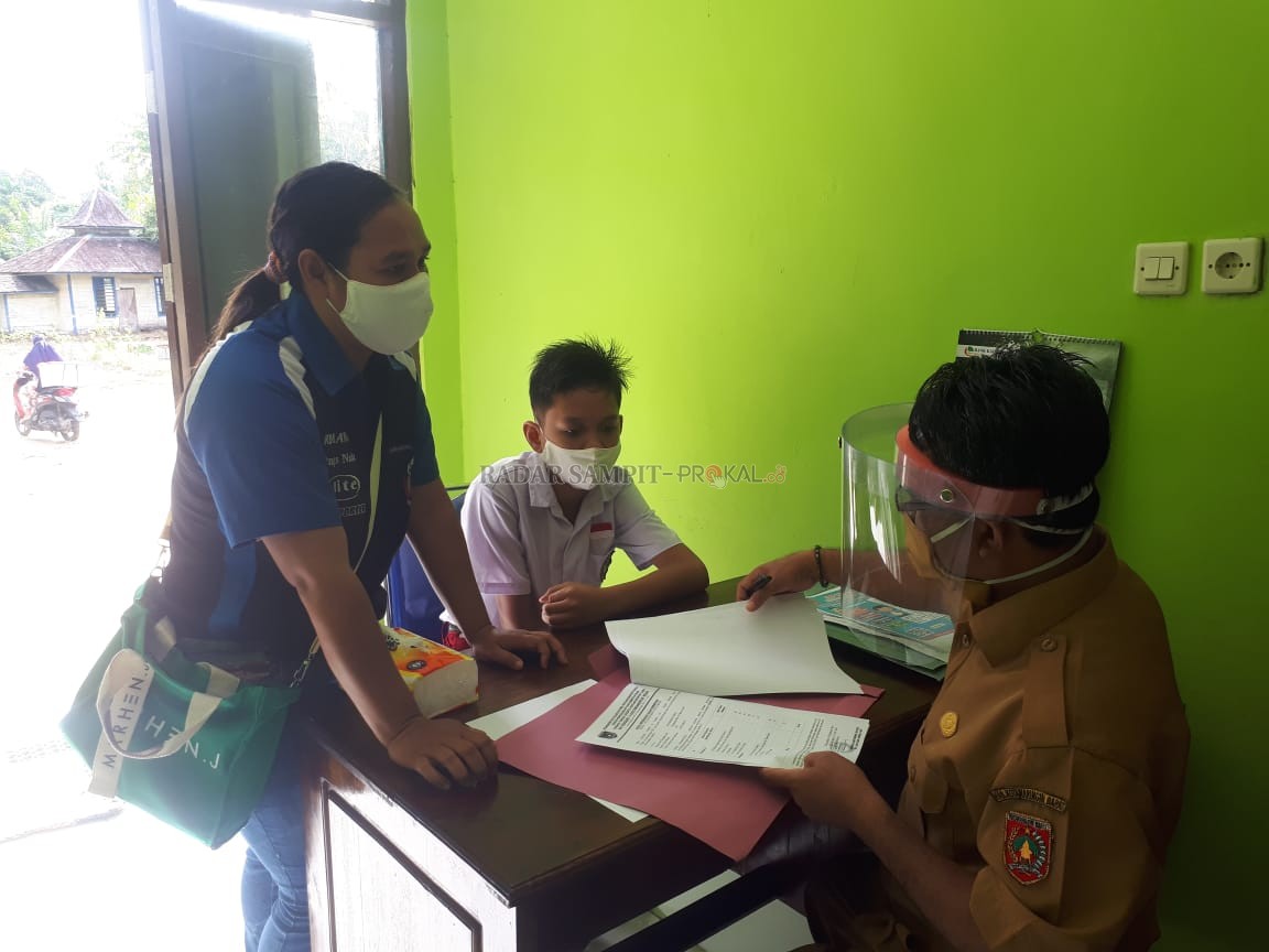 MURID BARU: Panitia PPDB SMPN 1 Kolam memeriksa kelengkapan berkas pendaftaran. (GUSTI HAMDAN/RADAR PANGKALAN BUN)