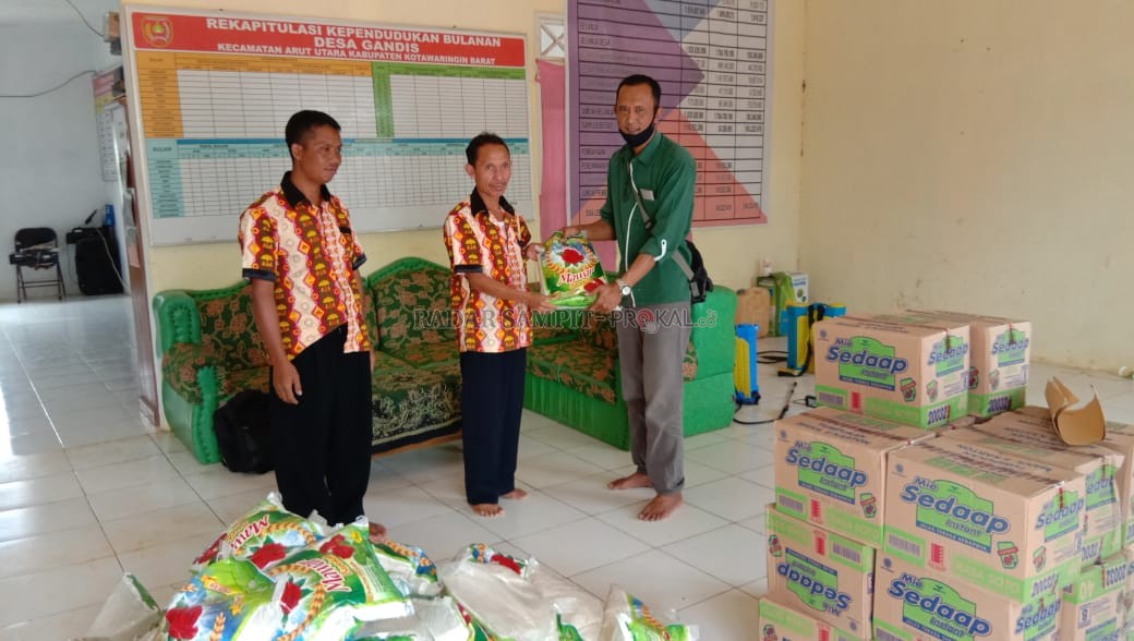 BANTUAN PANGAN ; Community Development Officer (CDO) PT. SINP-PBNA Suryono saat menyerahkan bantuan beras kepada Kepala Desa Gandis, Sanider yang selanjutnya akan dibagikan pada warga terdampak banjir. (SLAMET HARMOKO/RADAR PANGKALAN BUN)