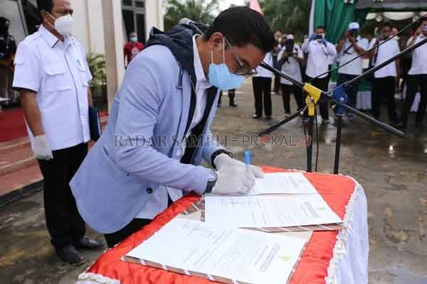 SEREMONIAL: Bupati Kotim Supian Hadi saat menandatangani berita acara dalam pelantikan kepala desa terpilih, hasil Pilkades serentak belum lama tadi. (PROKOM FOR RADAR SAMPIT )