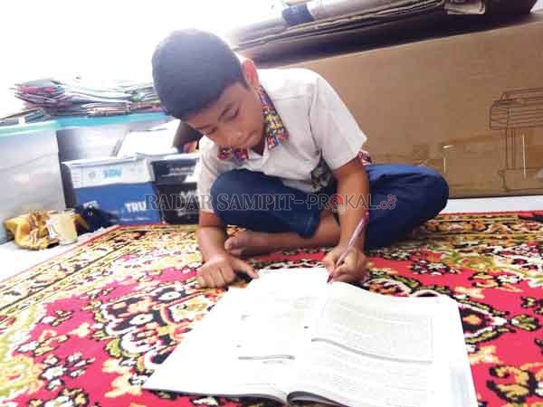 BELAJAR: Salah seorang murid yang bersekolah di SDN 4 MB Hilir ketika mengerjakan tugas sekolah di ruang kantor orang tuanya, Kamis (13/8).(HENY/RADAR SAMPIT)