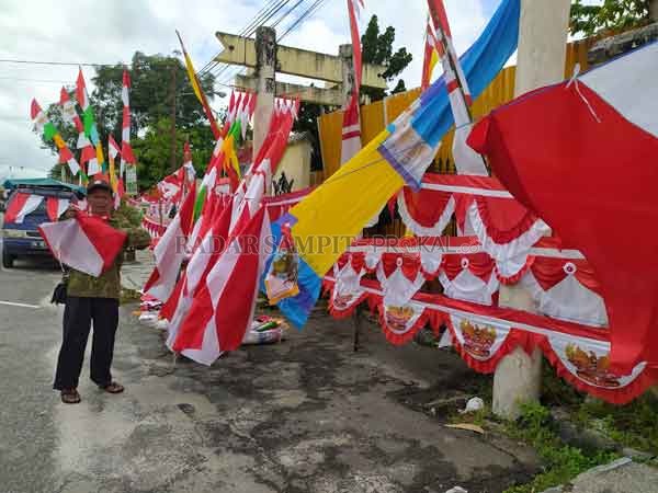 LARIS: Penjualan pernak pernik Agustusan di tengah pandemi Covid-19 justru mengalami peningkatan. Nampak Nana Suhana di lapaknya di Jalan Antasari depan Rujab Bupati Kobar, Sabtu (15/8).(SULISTYO/Radar Pangkalan Bun)