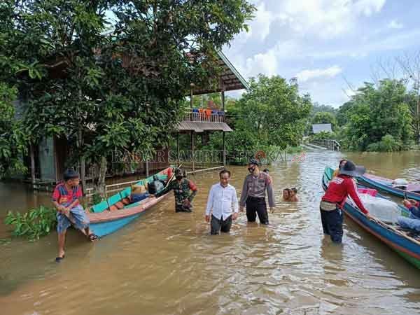 BANJIR: Camat Antang Kalang (kemeja putih) bersama anggota kepolisian dan TNI setempat membagikan bantuan paket sembako untuk warga di Desa Tumbang Kalang pekan lalu.(BERDIKARI FOR RADAR SAMPIT)