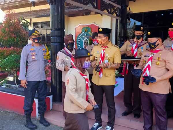 TERAPKAN PROTOKOL : Bupati Kotim Supian Hadi beserta jajaran saat membagikan masker kepada anggota Pramuka Kwarcab Kabupaten Kotim usia Upacara Peringatan HUT Pramuka ke-59, Kamis (17/9).(YUNI/RADAR SAMPIT )