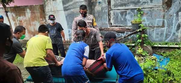 EVAKUASI: Anggota Polsek Arsel dan petugas kesehatan dibantu warga saat mengevakuasi jenazah Sunarti di sebuah kos-kosan Kelurahan Sidorejo, Arut Selatan, Minggu (27/9).(POLSEK ARSEL FOR RADAR SAMPIT)