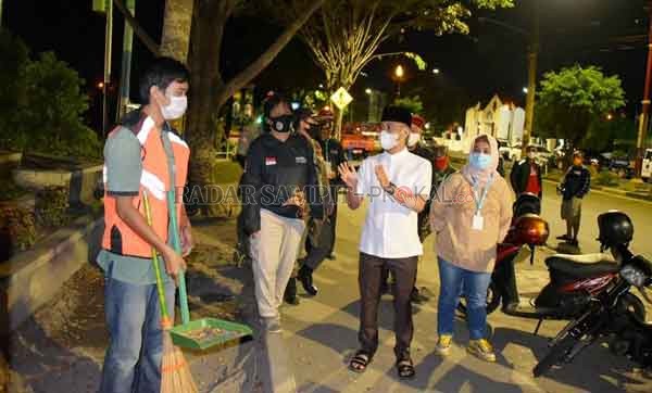 SANKSI : Wali Kota Palangka Raya, Fairid Naparin (tengah) saat memberikan pemahaman ke pada salah seorang pelanggar protokol kesehatan , yang tidak menggunakan masker dan mendapat  sangki n menyapu jalan, belum lama ini.(Humas for Radar Palalangka)