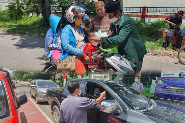 CEGAH COVID-19: Pengurus NU Kotim memasangkan masker kepada pengguna kendaraan roda dua. Sementara pengurus Muhammadiyah Kotim membagikan masker kepada pengendara mobil.(IST/RADAR SAMPIT)