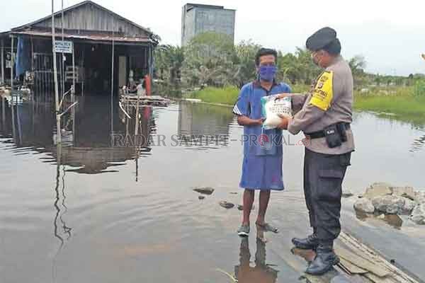 PEDULI: Bhabinkamtibmas Raja Seberang, Bripka Ahmad Japar saat menyerahkan bantuan beras kepada warga terdampak banjir luapan Sungai Arut, Minggu (1/11).(istimewa)