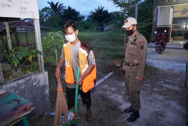 DITERTIBKAN : Anggota Satuan Tugas (Satgas) Penanganan Covid-19 Kota Palangka Raya ketika memberikan hukuman kepada para pelanggar protokol kesehatan, dengan bekerja sosial menyapu jalanan.(FOTO IST RADAR PALANGKA)