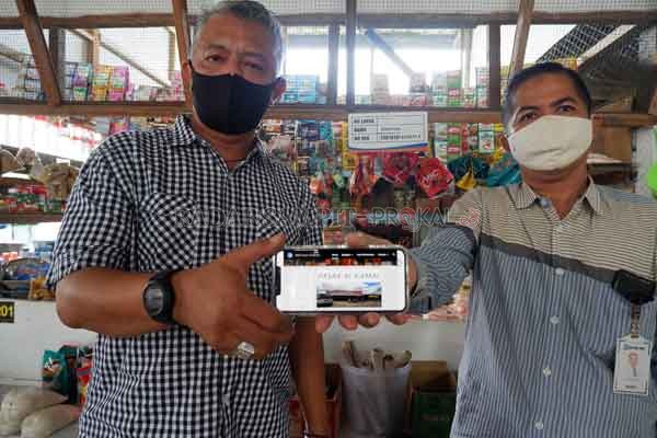 PASAR UNGGULAN:  Pengelola Pasar Alkamal Supriyadi Elyas bersama Asisten Manager BRI Cabang Sampit Komarudin, memperlihatkan layanan web pasar. Lewat layanan ini pembeli bisa belanja tanpa harus datang langsung ke Pasar Alkamal.(USAY NOR RAHMAD/RADAR SAMP