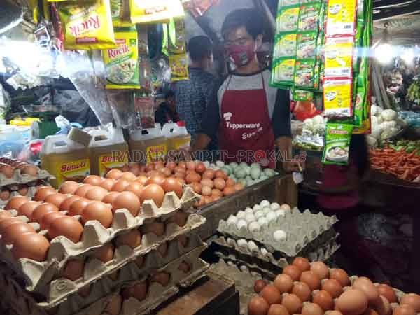 BAHAN POKOK: Seorang pembeli yang sedang memilih telur di Pasar Tradisional Jalan MT Haryono, Rabu (16/12) malam.(HENY/RADAR SAMPIT)