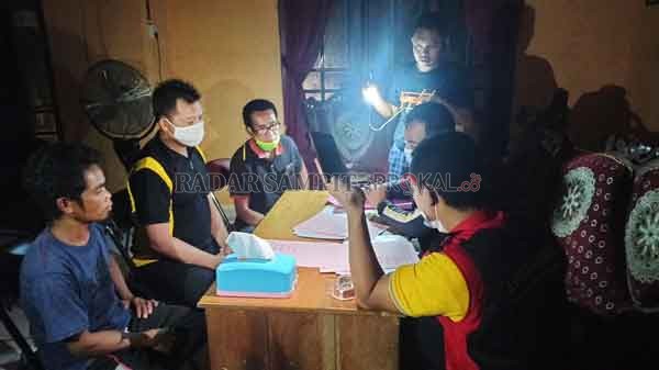 KURANG CAHAYA: Penyidik Kejaksaan Negeri Lamandau harus menggunakan senter di handphone mereka masing-masing saat sedang meneliti berkas dan menyerahkan berkas acara penggeledahan Kantor Desa Bunut, akhir pekan kemarin.(RIA MEKAR/RADAR PANGKALAN BUN)