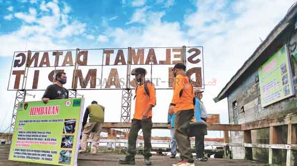 PAPAN IMBAUAN: Petugas BKSDA bersama petugas kecamatan dan kelurahan memasang papan imbauan  mewaspadai terjadinya serangan buaya di Kelurahan Mentaya Seberang, Kecamatan Seranau, Jumat (15/1).(USAY NOR RAHMAD/RADAR SAMPIT)