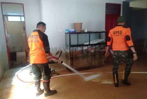 BEKAS BANJIR : Kepala BPBD Mura Kariadi, saat menyemprot lumpur di salah satu rumah warga Barabai, Kecamatan Hulu Sungai Tengah pascabanjir, Senin (18/1).(BPBD/RADARSAMPIT)