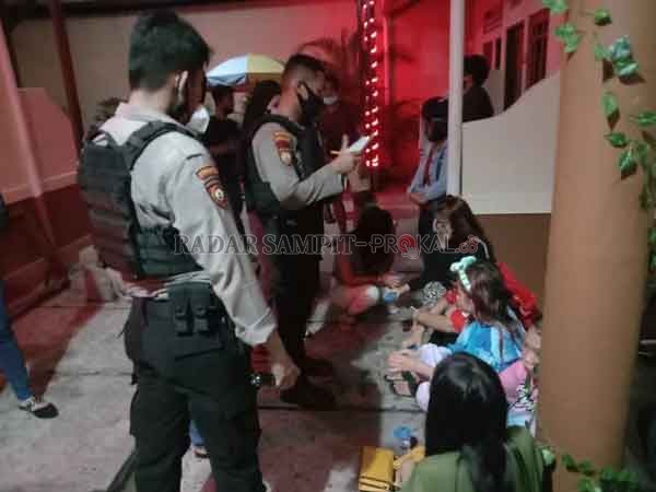 DIPERIKSA : Petugas kepolisian saat melakukan pendataan puluhan remaja yang digerebek di Wisma Pisces Palangka Raya, lantaran di lokasi tersebut dilaporkan warga jadi tempat transaksi prostitusi online, Minggu (31/1) dini hari.(istimewa)