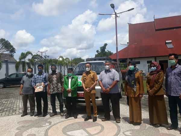 HIBAH : Wali Kota palangka Raya Fairid Naparin bersama pengurus DPC NU Kota Palangka Raya berlatar belakang mobil hibah dari pemerintah kota.(DODI/RADAR PALANGKA)