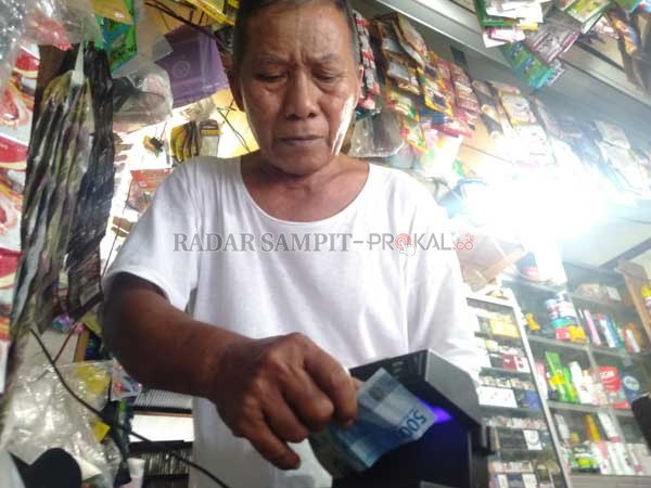 CEMAS: Seorang pedagang, Kamrul Hadi, menunjukkan alat deteksi uang palsu yang ia beli agar tidak menjadi korban peredaran uang palsu, Minggu (21/2).(FAHRY/RADAR SAMPIT)