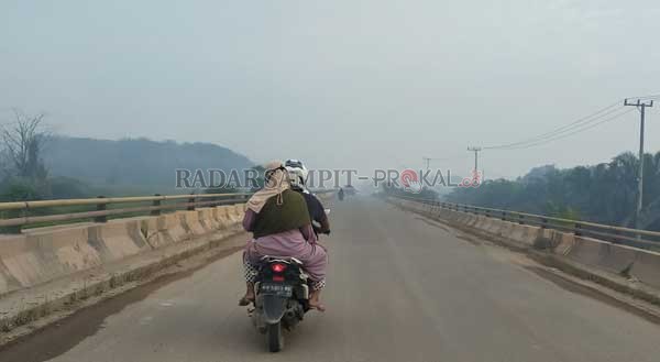 DISELIMUTI ASAP : Salah seorang pengendara melintas di ruas Jalan Pangkalan Bun - Kotawaringin Lama. Jalur tersebut mulai diselimuti kabut asap akibat karhutla, Minggu (28/2).(SULISTYO/RADAR PANGKALAN BUN)