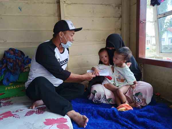 PEDULI: Salah seorang warga menyerahkan bantuan kepada keluarga bayi, Jumat (21/5).(ISTIMEWA/RADAR PANGKALAM BUN)