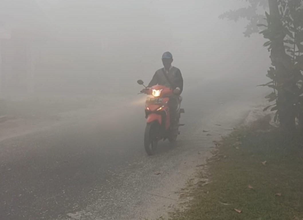 KABUT ASAP : Pengendara bermotor sambil menyalakan lampu melintasi jalan yang berselimut kabut asap tebal di Kota Sampit, Kotawaringin Timur, Senin (2/10/2023) pagi. (YUNI/RADAR SAMPIT)