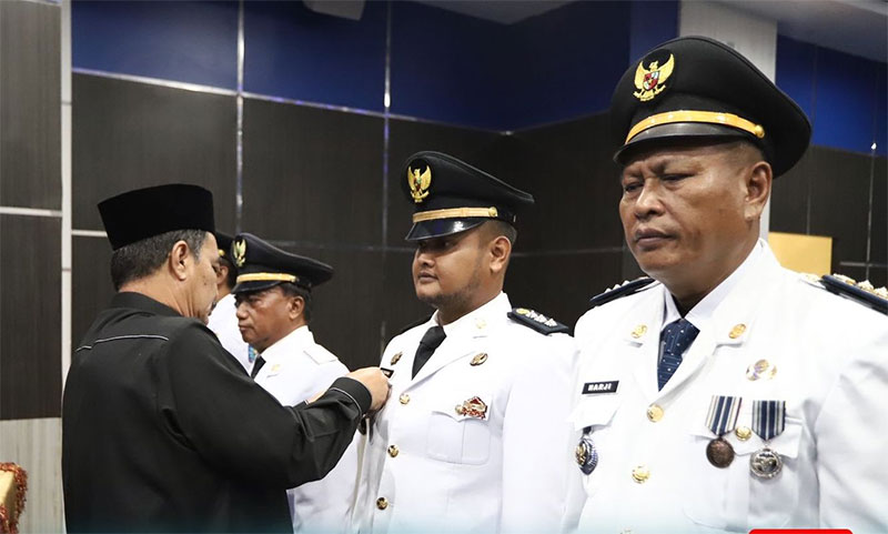 Asisten III Setda Rohul H Edi Suherman memasang tanda jabatan kepada 4 pejabat Administrator Eselon III Camat usai melantik dan mengambil sumpah jabatan pejabat Eselon III di ingkungan Pemkab Rohul.